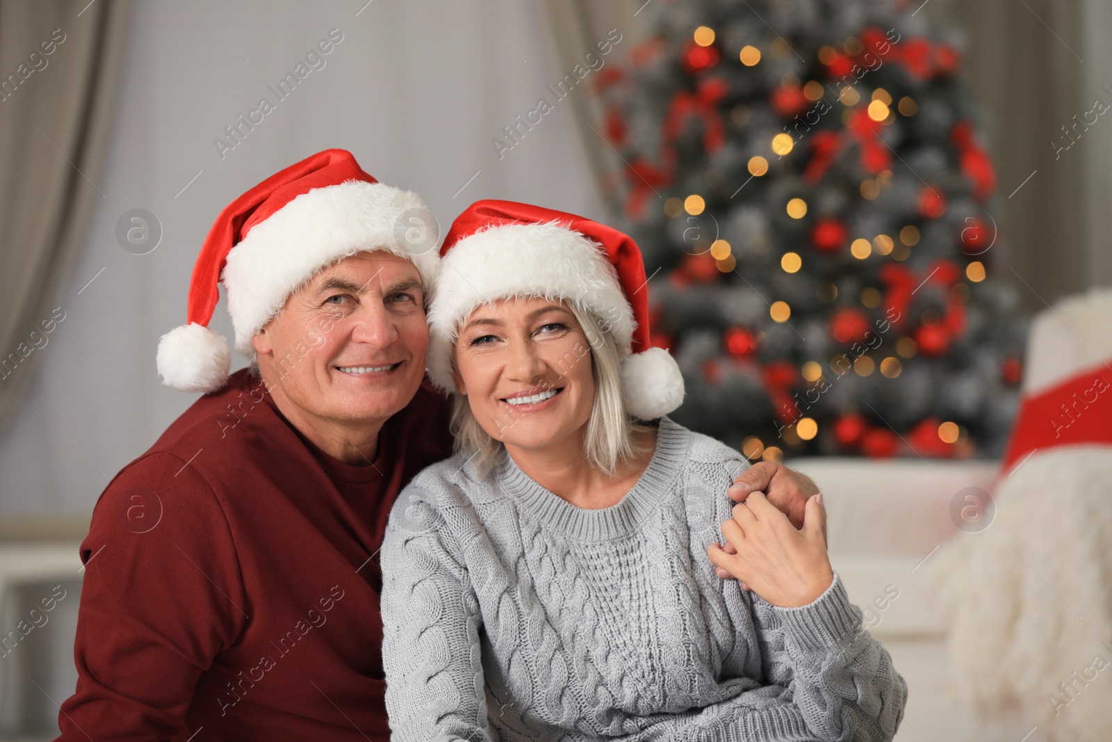 Photo of Happy mature couple in Santa hats at home. Christmas celebration