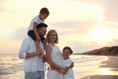 Photo of Happy family on sandy beach near sea at sunset