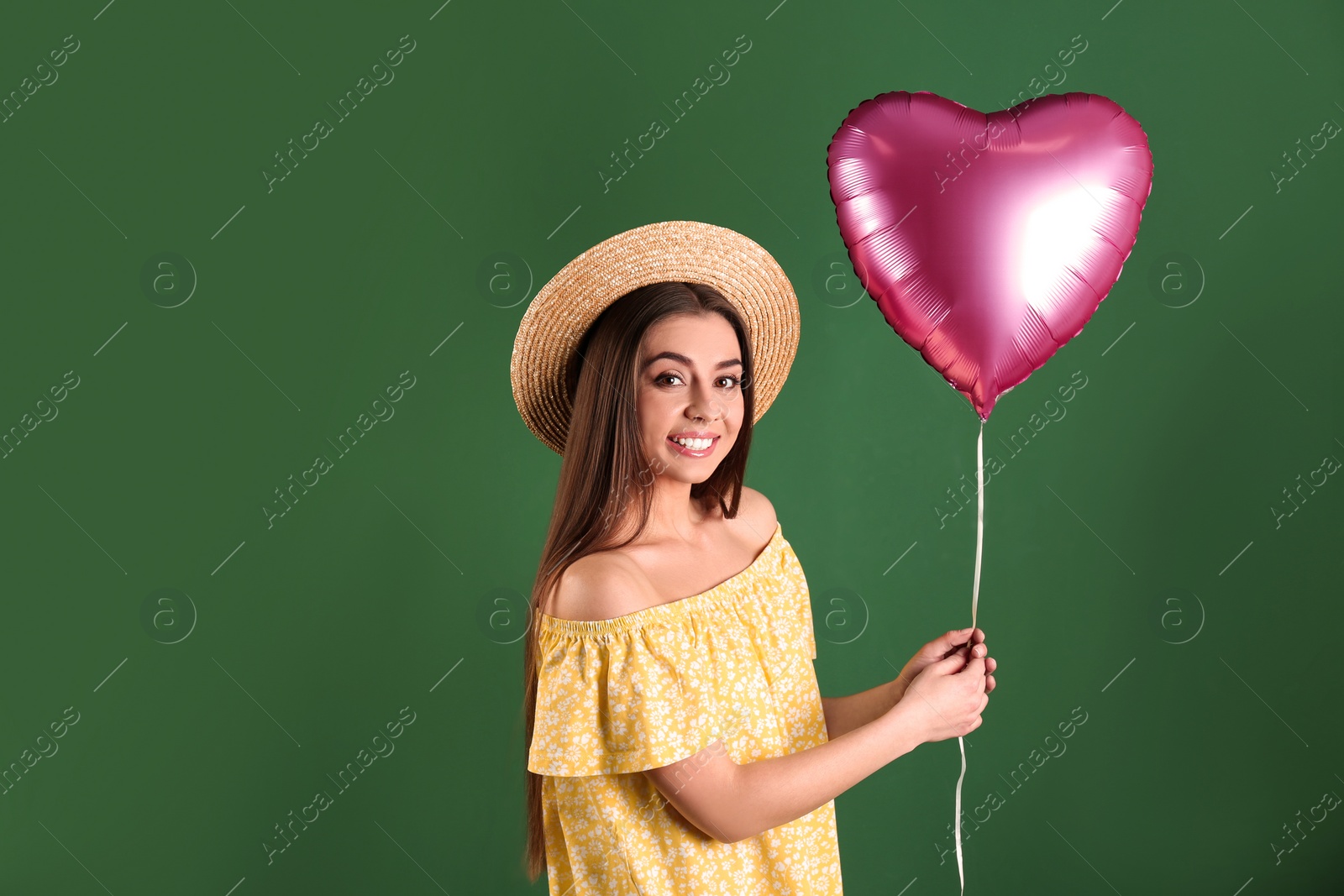 Photo of Portrait of young woman with heart shaped balloon on color background