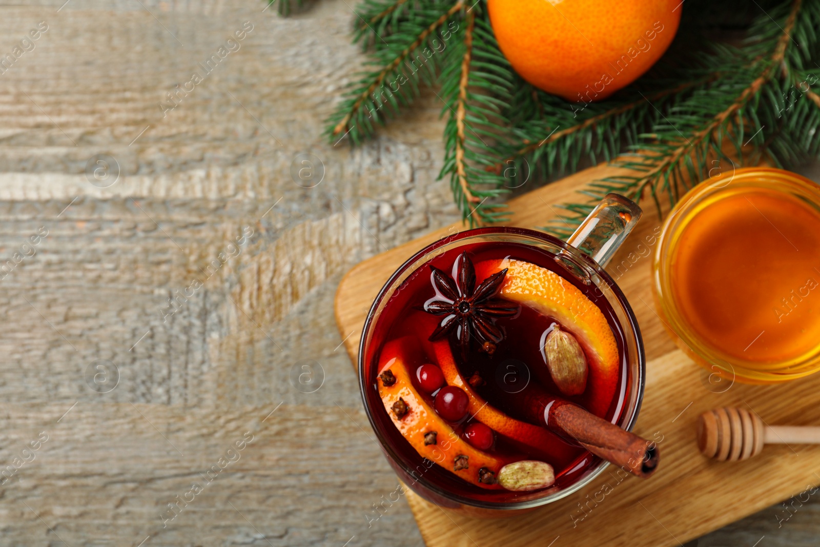 Photo of Glass cup of tasty mulled wine on wooden background, flat lay. Space for text