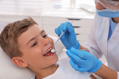 Photo of Dentist examining little boy's teeth in modern clinic