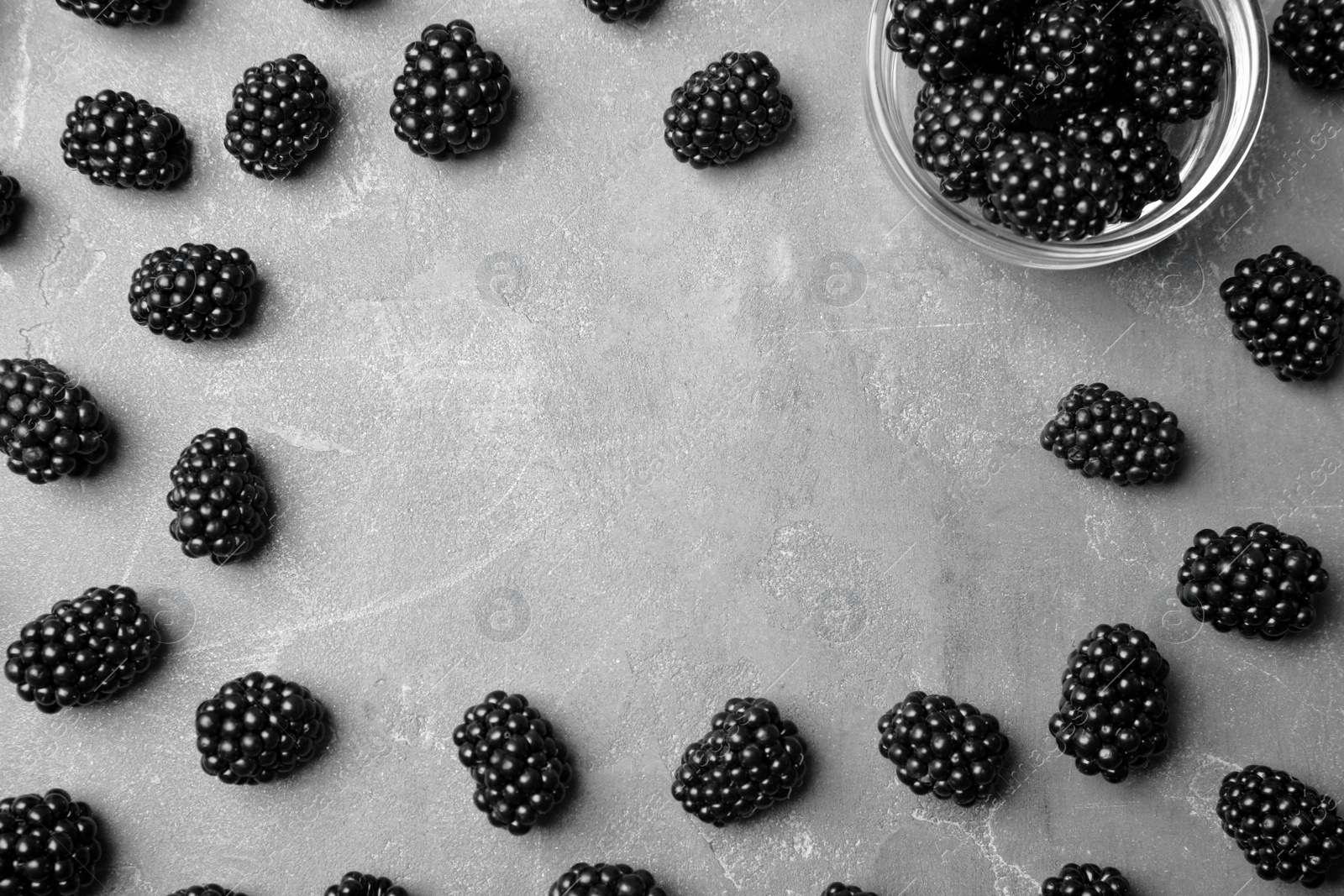 Photo of Frame made of tasty blackberries on grey table, top view with space for text