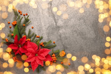 Flat lay composition with traditional Christmas poinsettia flowers and space for text on grey table, bokeh effect 