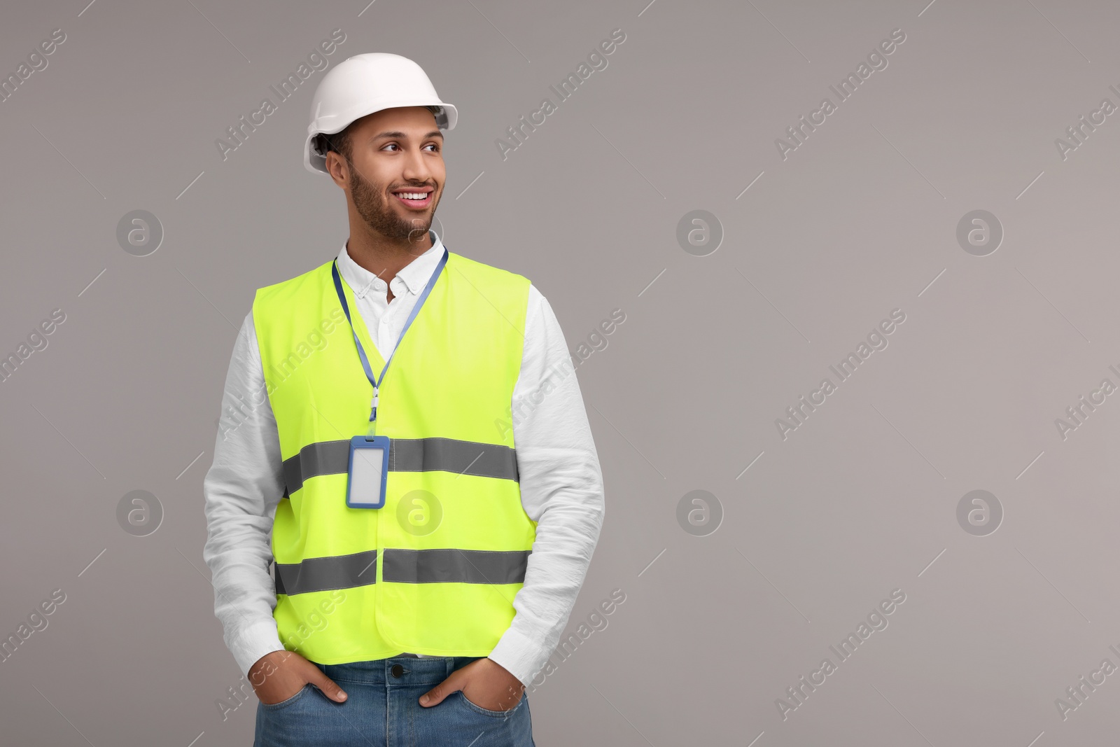 Photo of Engineer with hard hat and badge on grey background, space for text