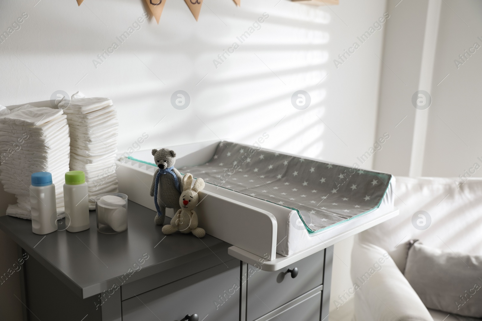 Photo of Chest of drawers with changing tray and pad in baby room. Interior design