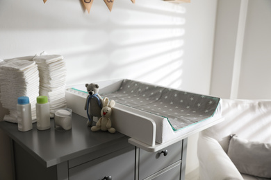 Photo of Chest of drawers with changing tray and pad in baby room. Interior design