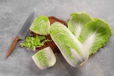 Photo of Whole and cut fresh Chinese cabbages on light grey table, flat lay