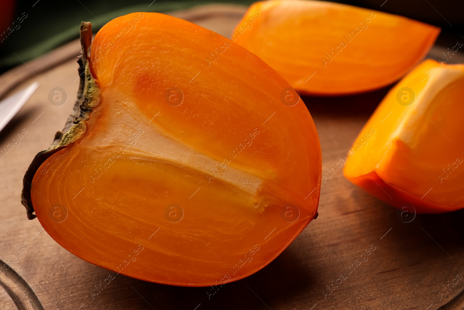 Photo of Pieces of delicious ripe persimmons on wooden table, closeup