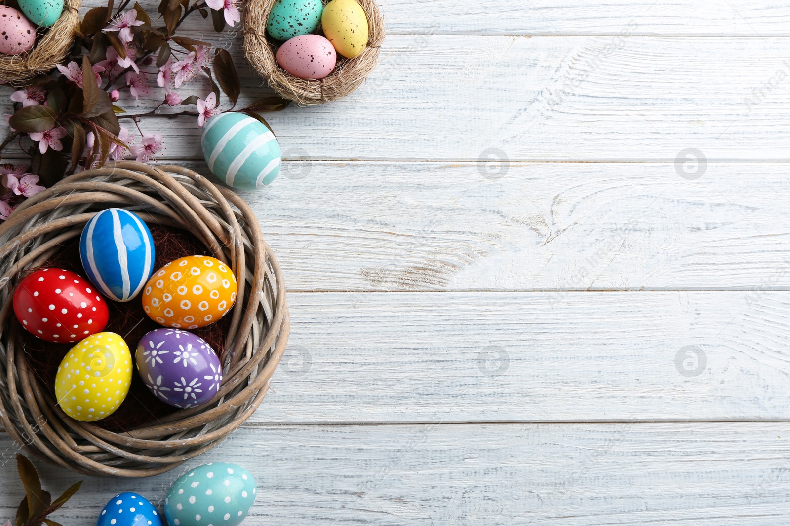 Photo of Flat lay composition with painted Easter eggs and blossoming branches on wooden background. Space for text