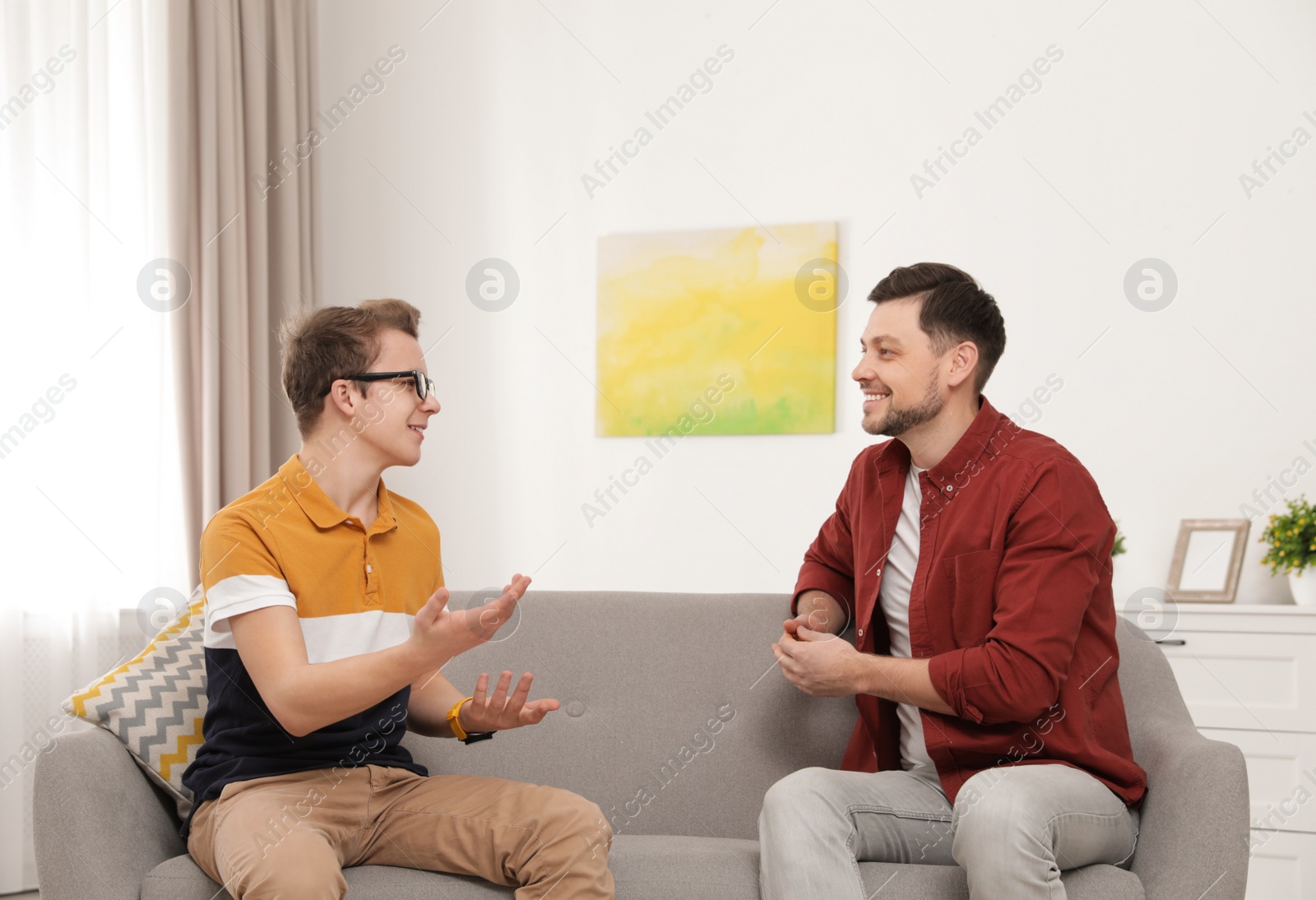 Photo of Father talking with his teenager son at home