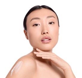 Photo of Beautiful young Asian woman with body cream smear on shoulder against white background