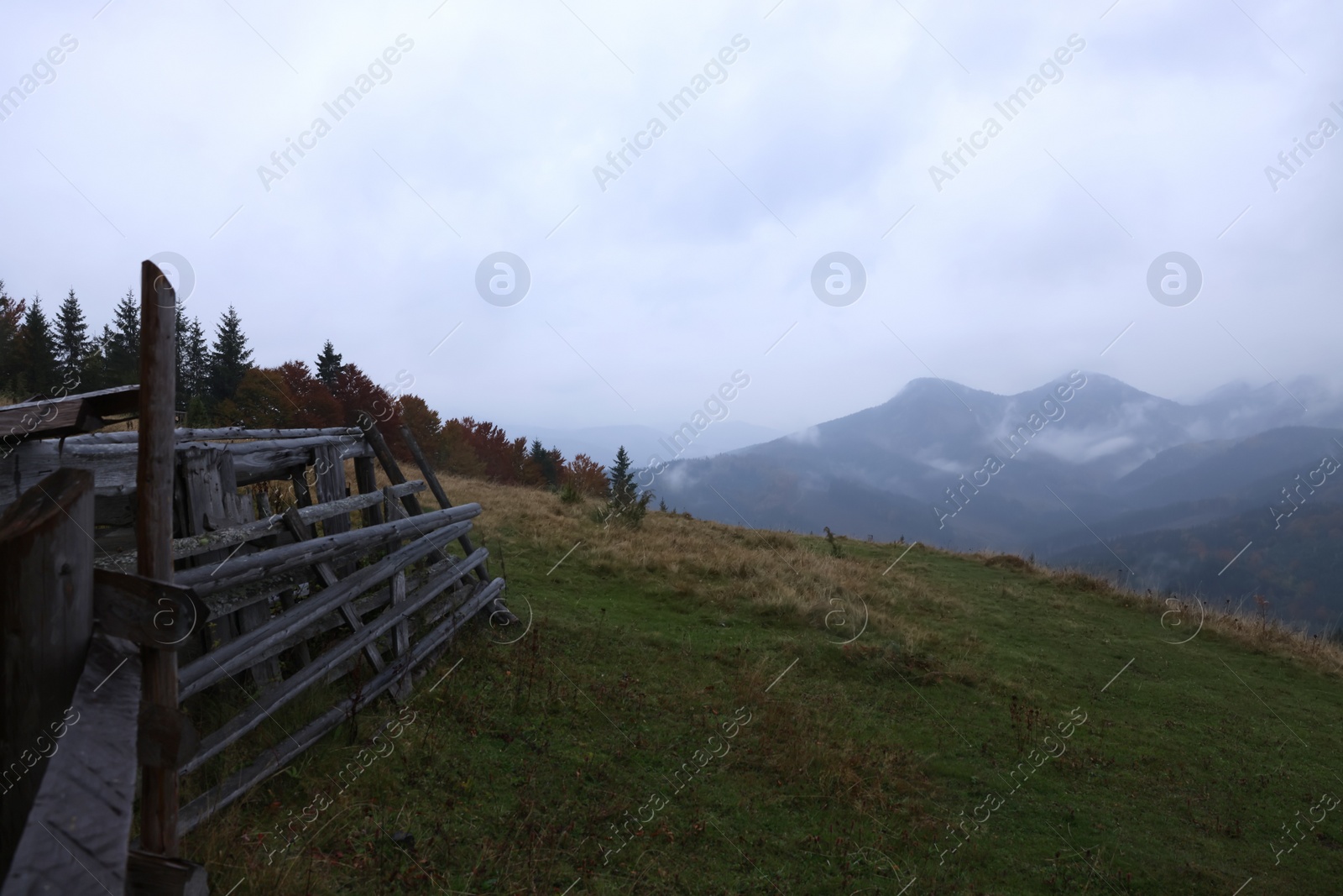 Photo of Old wooden fence in mountains covered with fog