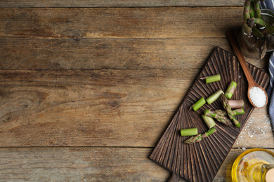 Photo of Fresh raw asparagus on wooden table, flat lay. Space for text