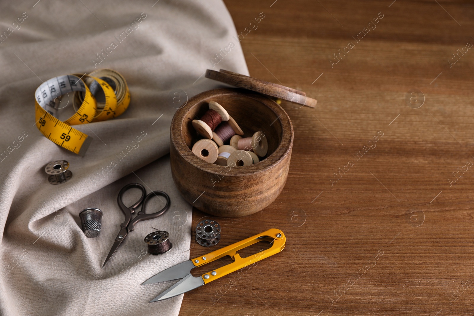 Photo of Set of sewing supplies and accessories on wooden table, space for text