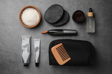 Photo of Compact toiletry bag, spa stones and different cosmetic products on grey textured background, flat lay