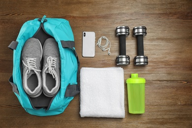 Photo of Sports bag and gym equipment on wooden background, top view