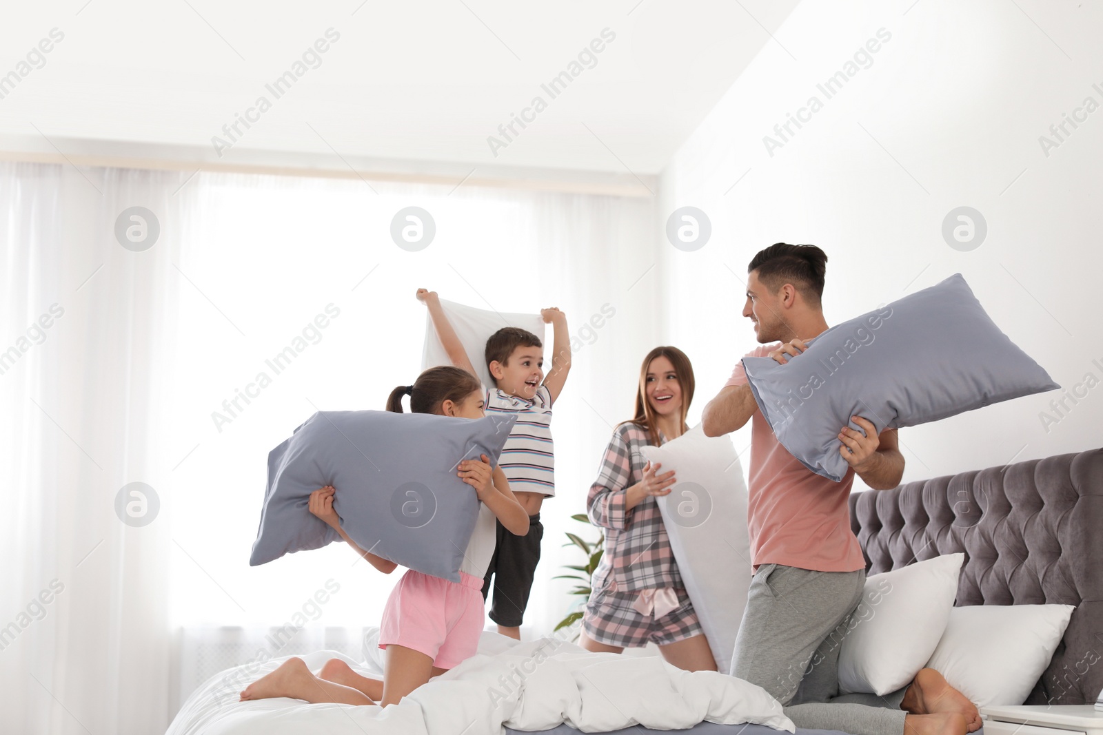 Photo of Happy family having pillow fight in bedroom