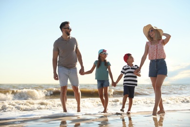 Photo of Happy family walking on sandy beach near sea