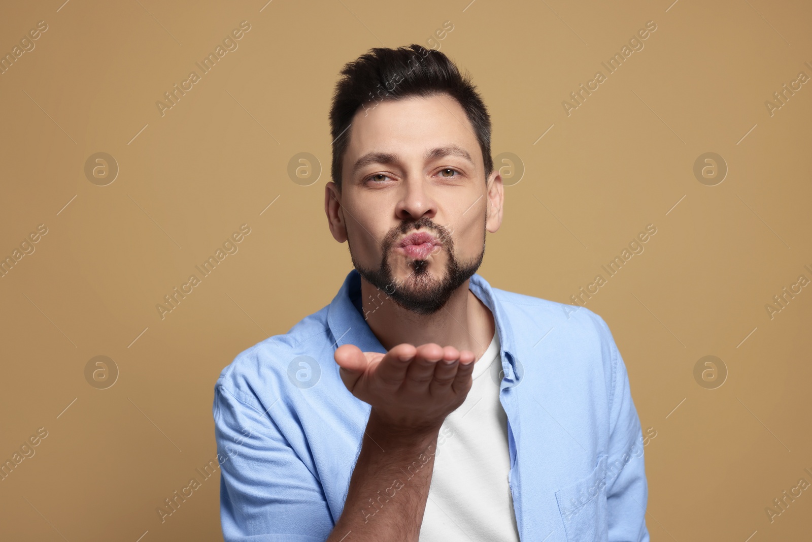 Photo of Handsome man blowing kiss on beige background