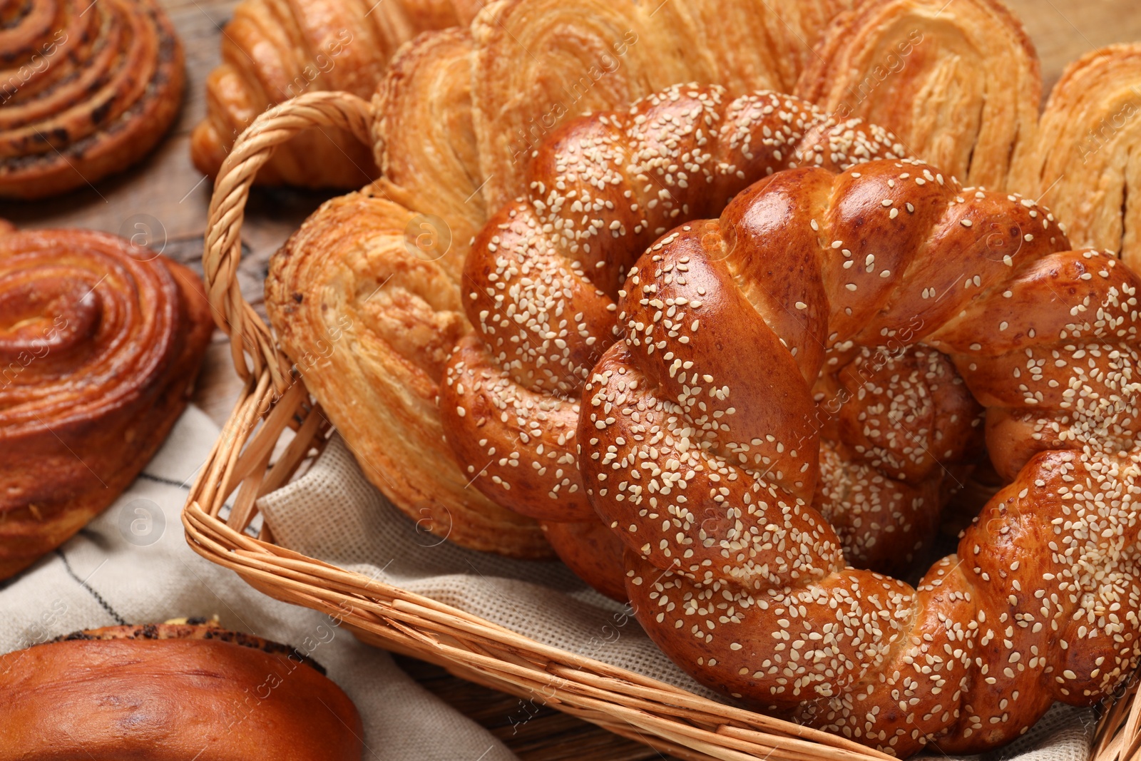 Photo of Wicker basket with different tasty freshly baked pastries on table, above view