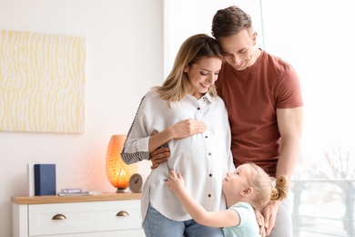 Photo of Young pregnant woman with her family at home