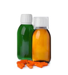 Photo of Bottles of syrups, measuring cup with pills on white background. Cough and cold medicine