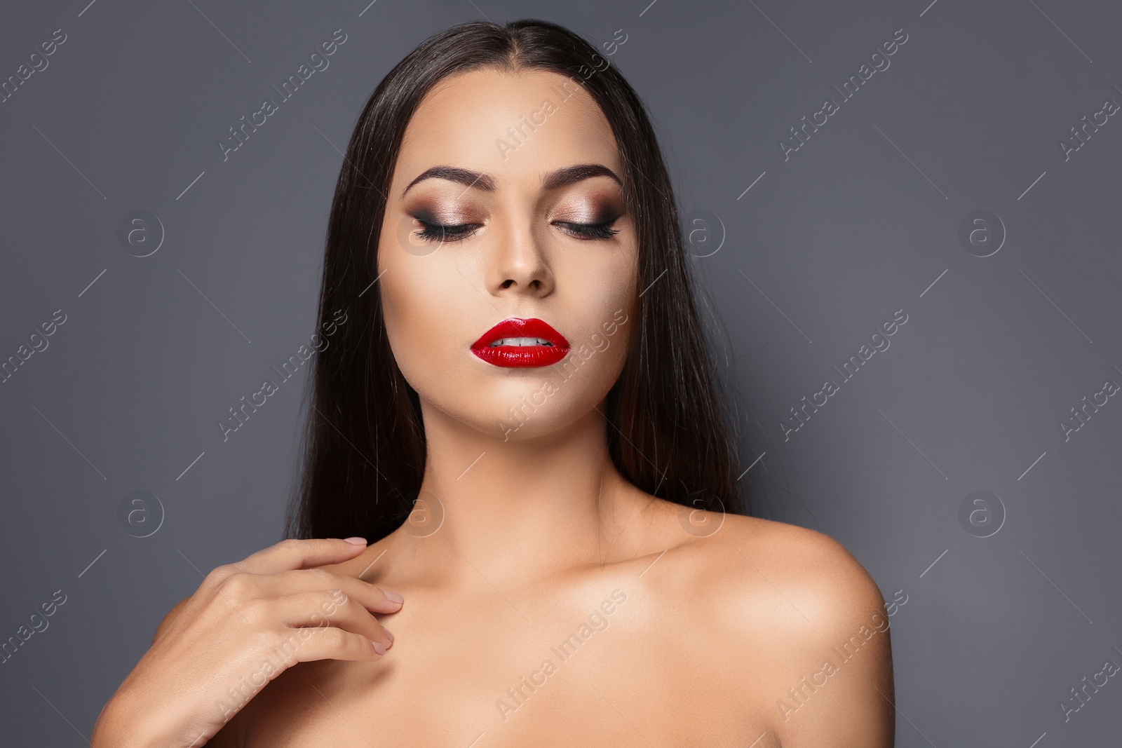 Photo of Portrait of beautiful young woman with red glossy lips on gray background