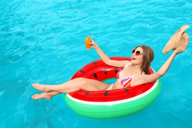 Photo of Young woman with cocktail in pool on sunny day