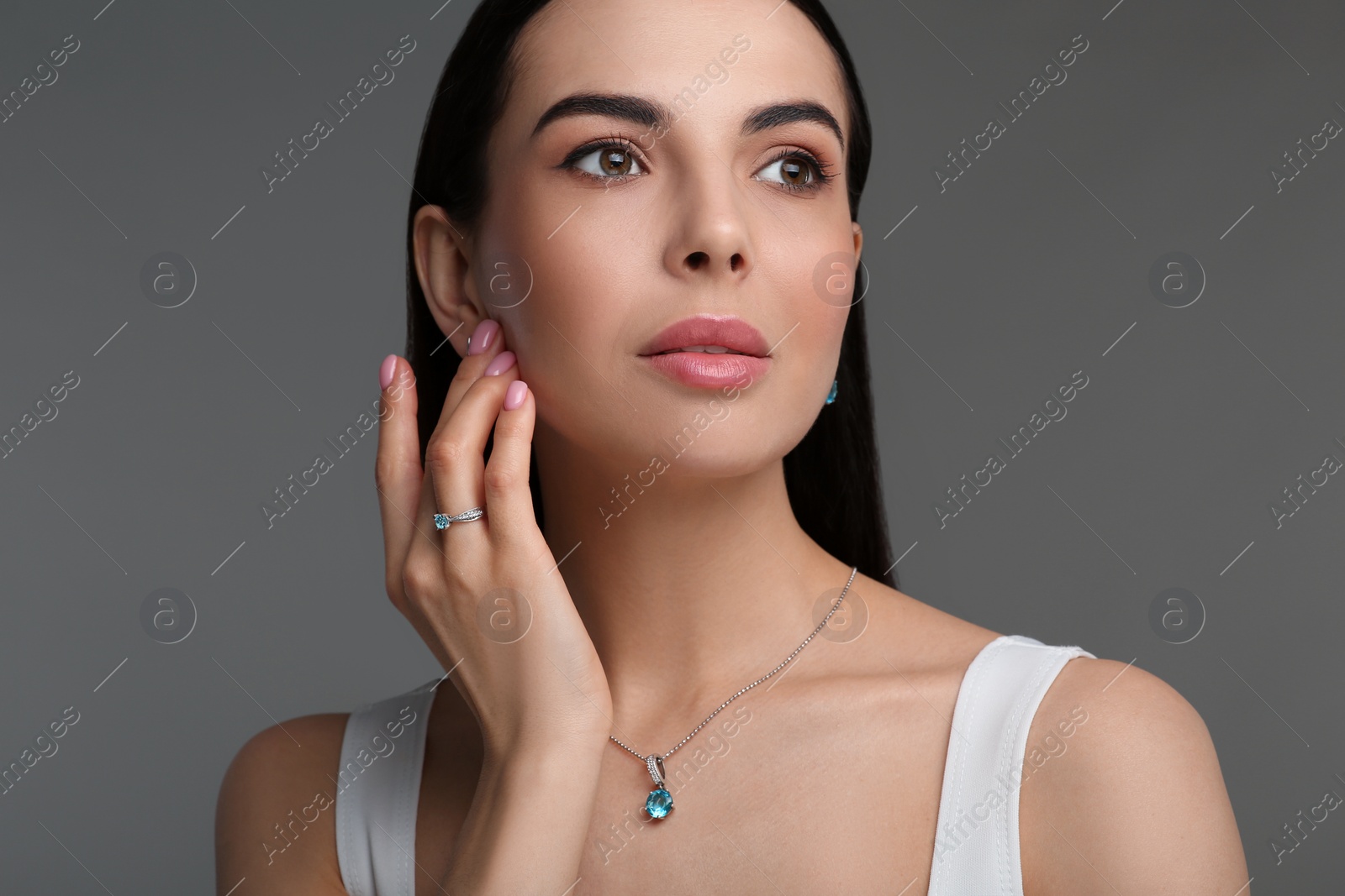 Photo of Beautiful young woman with elegant jewelry on dark grey background