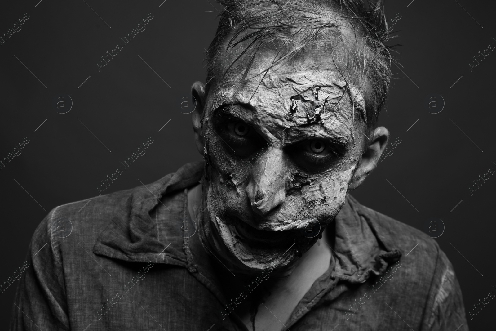 Photo of Scary zombie on dark background, black and white effect. Halloween monster