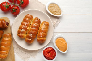 Photo of Delicious sausage rolls and ingredients on white wooden table, flat lay. Space for text