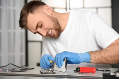 Photo of Technician repairing mobile phone at table in workshop, closeup