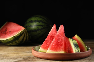 Photo of Plate with slices of juicy watermelon on wooden table, space for text