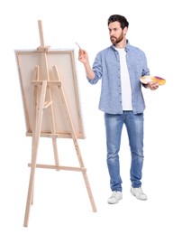 Photo of Man painting against white background. Using easel to hold canvas