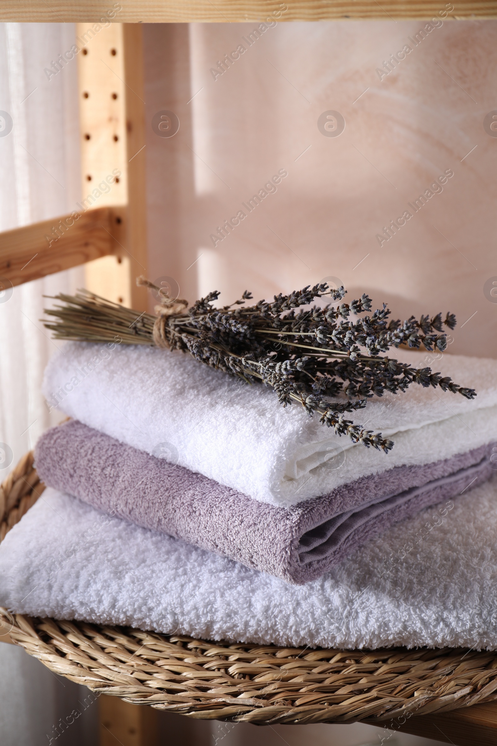 Photo of Stacked soft towels and lavender on shelf indoors