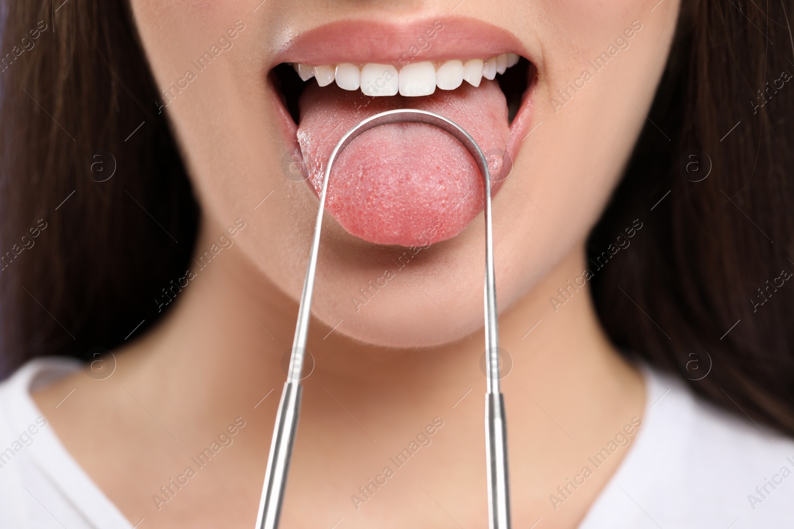 Photo of Woman brushing her tongue with cleaner, closeup