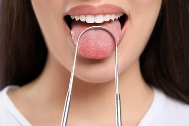 Woman brushing her tongue with cleaner, closeup