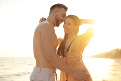 Happy young couple on beach at sunset