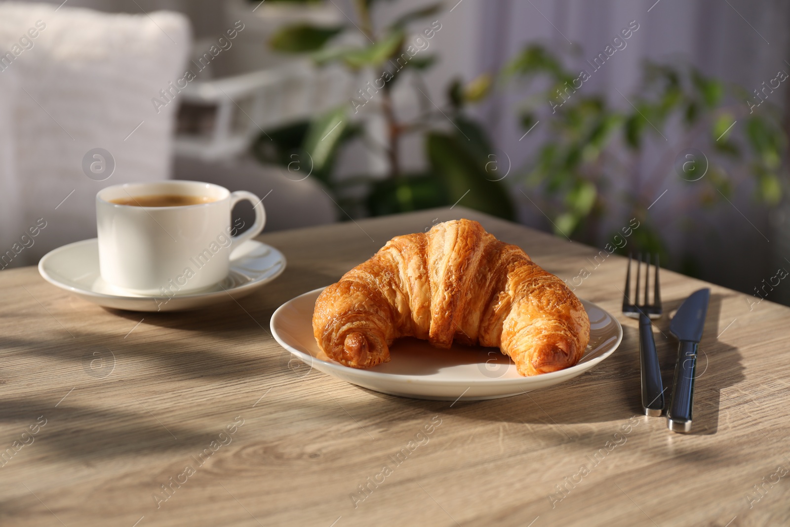 Photo of Delicious fresh croissant served with coffee on wooden table