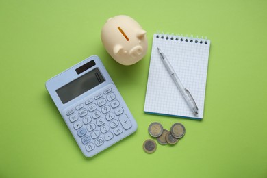 Photo of Piggy bank, notebook, calculator and coins on light green background, flat lay
