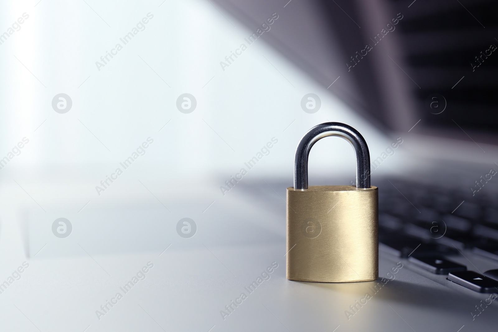 Photo of Metal padlock on laptop keyboard, space for text. Cyber security concept