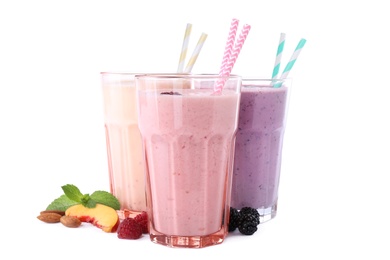Photo of Different tasty fresh milk shakes in glasses with ingredients on white background