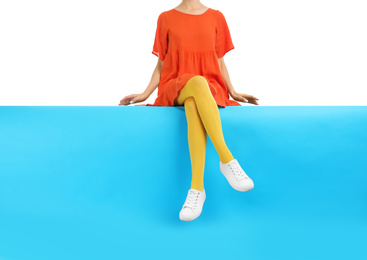 Photo of Woman wearing yellow tights and stylish shoes sitting on color background, closeup