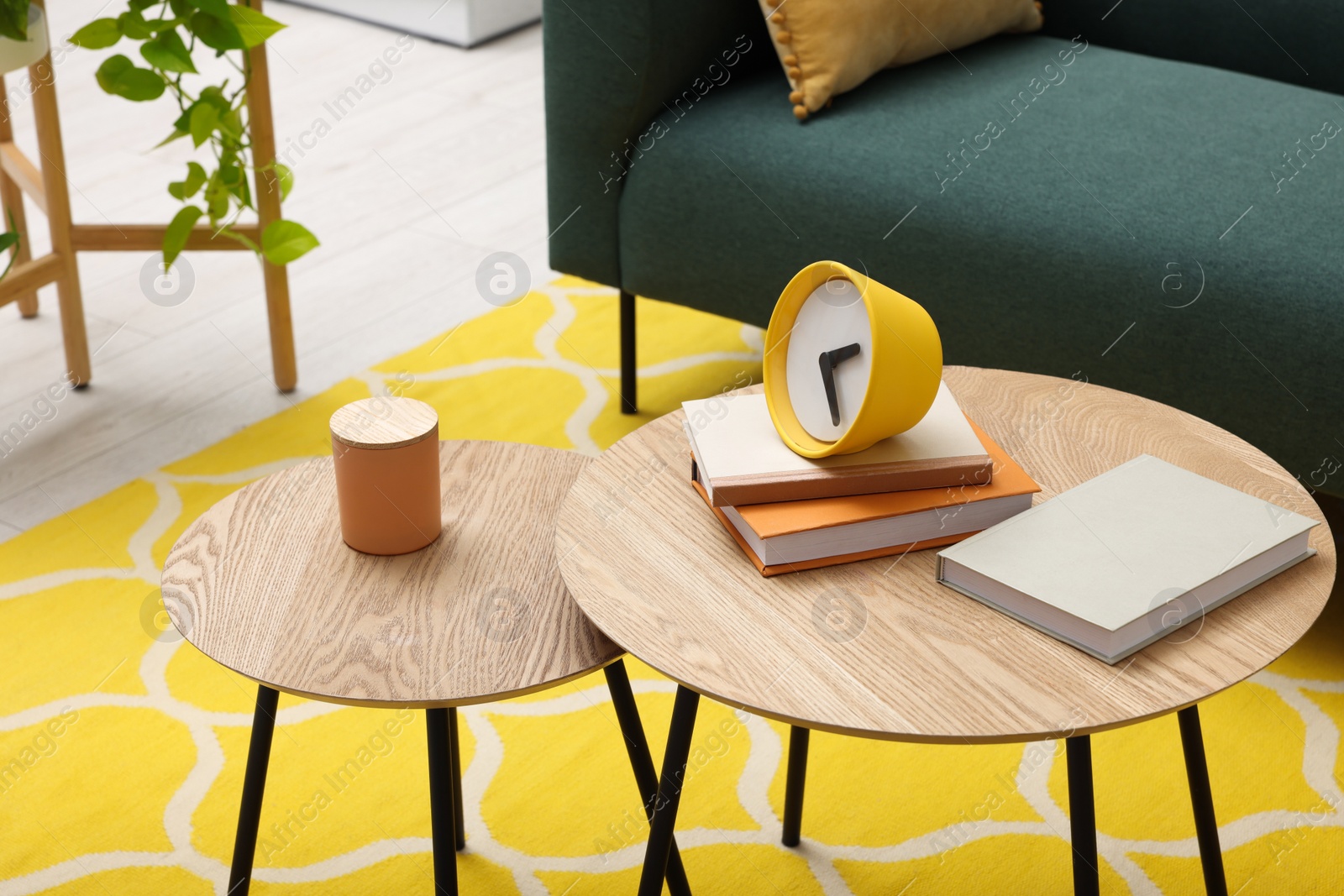 Photo of Spring interior. Yellow clock, books and candle on wooden table in living room