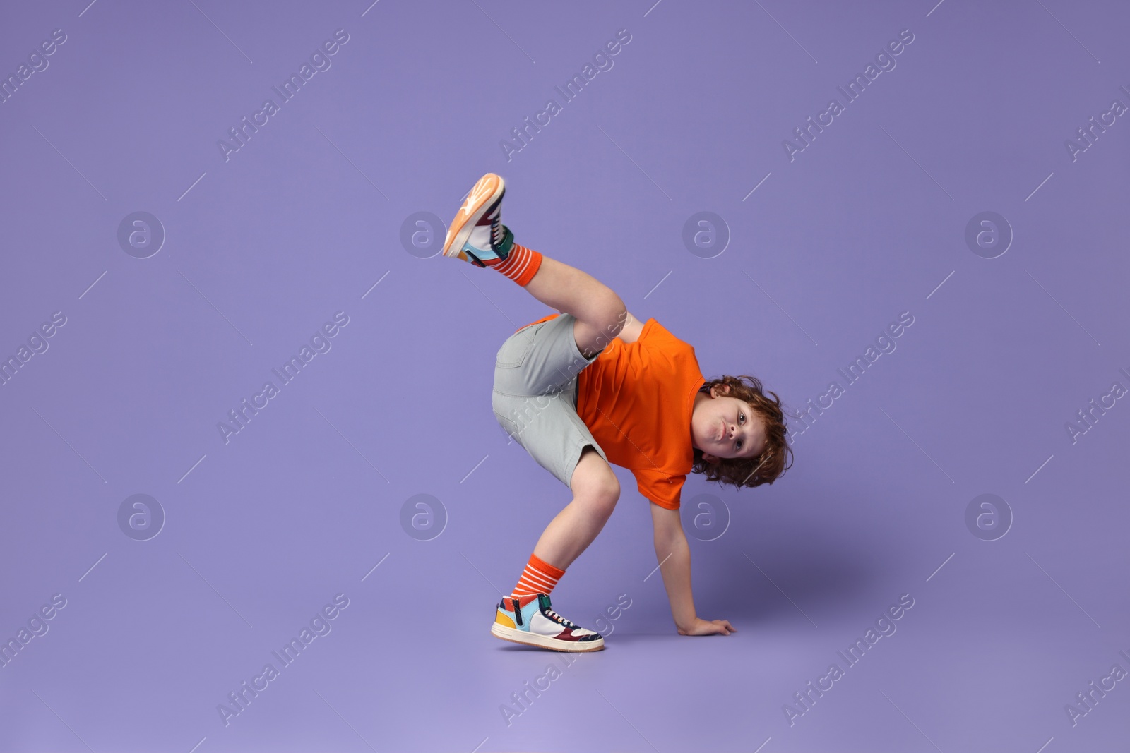 Photo of Happy little boy dancing on violet background