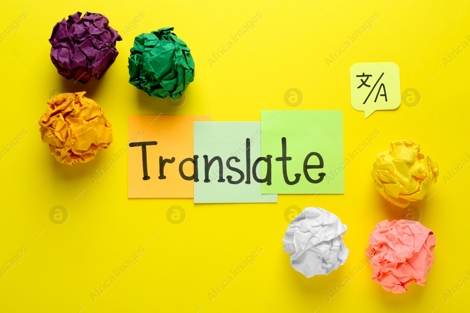 Photo of Word Translate made with sticky notes near crumpled paper balls on yellow background, flat lay