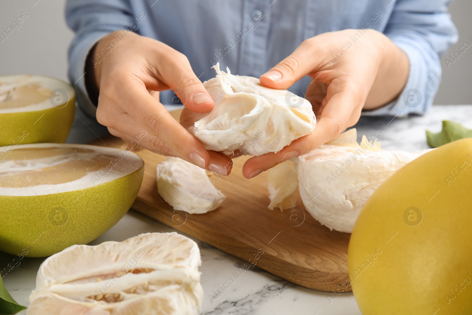 Photo of Woman with tasty ripe pomelo at white marble table, closeup