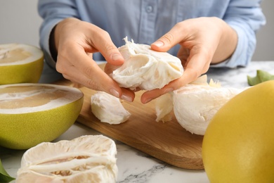 Photo of Woman with tasty ripe pomelo at white marble table, closeup