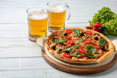 Tasty homemade pizza and mugs with beer on wooden table