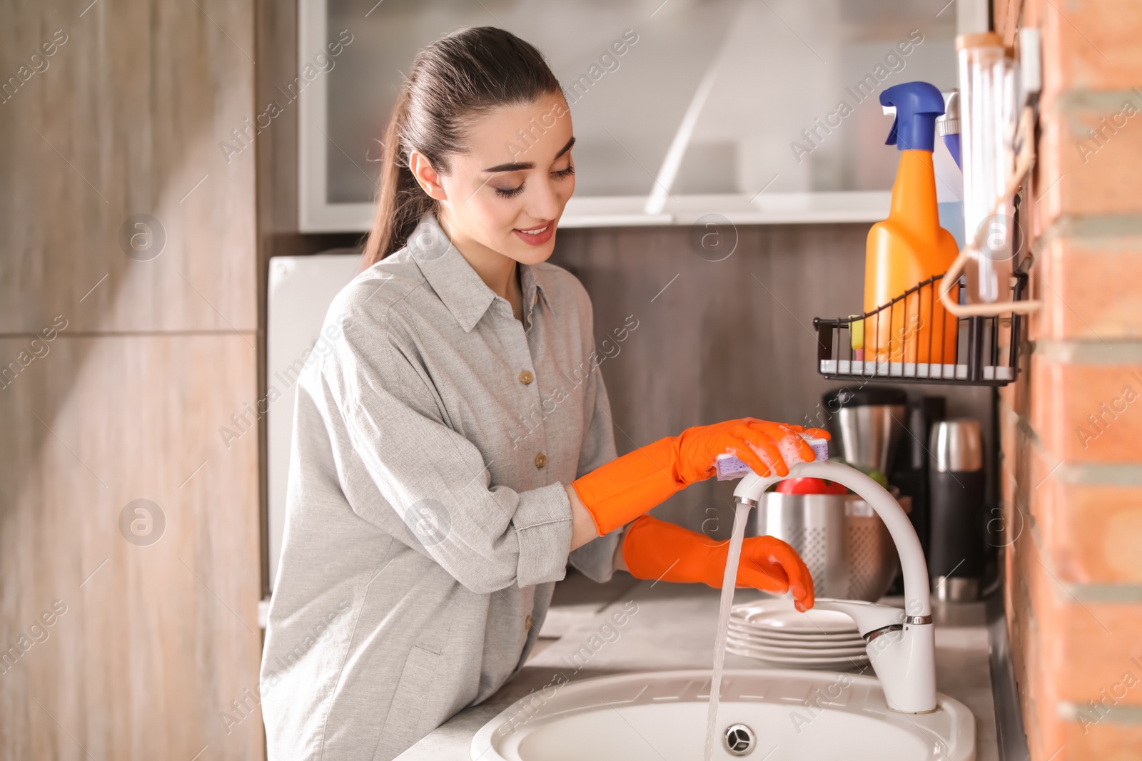 Photo of Young woman cleaning tap in kitchen